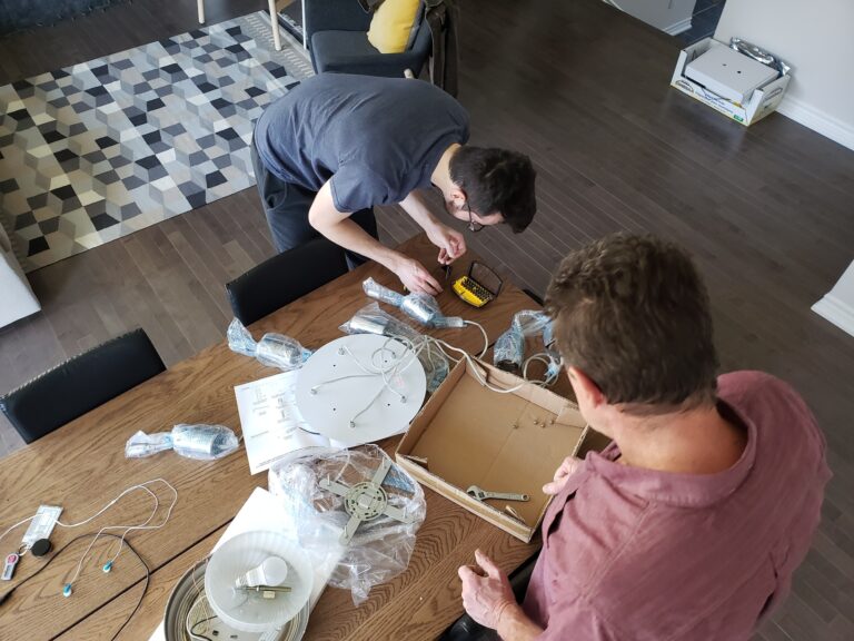 Group of men working on electric wiring for chandelier